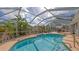 Backyard pool enclosed by a screened lanai, surrounded by lush tropical landscaping and patio furniture at 6583 Waterford Cir, Sarasota, FL 34238