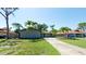 A single-Gathering home featuring a well-manicured lawn, mature palm trees, and a long private driveway at 7019 10Th S St, St Petersburg, FL 33705