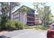 Low-angle daytime view of a condo with a screened balcony bordered in red and surrounded by trees and other greenery at 7500 40Th W Ave # 209, Bradenton, FL 34209