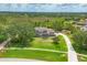 Expansive aerial view of a home with a meticulously maintained lawn, long driveway, and scenic wooded backdrop at 8015 Panther Ridge Trl, Bradenton, FL 34202