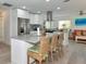 Modern kitchen with stainless steel appliances, white cabinets, mosaic backsplash, and a spacious island with seating at 8152 Seashell St, Englewood, FL 34224
