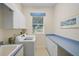 Laundry room with blue counters, cabinets, window and appliances at 901 Reflection Way, Osprey, FL 34229