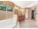 Relaxing bathroom featuring a soaking tub, a large window with view, dual sinks and vanity, and tiled flooring at 919 80Th Nw St, Bradenton, FL 34209