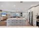 Open kitchen featuring a large island, stainless steel refrigerator, white cabinets, and an open layout to living area at 10304 Sandpiper W Rd, Bradenton, FL 34209
