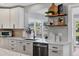 Kitchen area features white cabinetry, a stainless steel dishwasher, and open shelving at 10304 Sandpiper W Rd, Bradenton, FL 34209