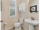 Well-lit half bathroom with a pedestal sink, toilet, and window, perfect for guests at 11925 Brookside Dr, Bradenton, FL 34211