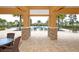View of the community pool through the columns of the patio, surrounded by palm trees and lounge chairs at 11925 Brookside Dr, Bradenton, FL 34211