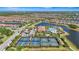 Aerial view of a community showcasing tennis courts, pool, clubhouse, and lake amid well-maintained landscapes at 12020 Legacy Estates Blvd, Sarasota, FL 34238