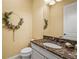 Small powder room features a single sink with a marble counter, a toilet, and a decorative wreath at 12020 Legacy Estates Blvd, Sarasota, FL 34238