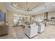 Open-concept living room with tray ceilings, tile floors, neutral tones, and a kitchen view at 12020 Legacy Estates Blvd, Sarasota, FL 34238