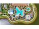 Aerial view of a luxurious community pool area with a waterpark and sun loungers near a lake at 12020 Legacy Estates Blvd, Sarasota, FL 34238