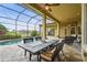 Covered patio with dining set overlooks an enclosed pool area, landscaping, a lake, and houses at 12020 Legacy Estates Blvd, Sarasota, FL 34238