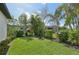 Lush backyard featuring tropical plants, mature landscaping and a red birdhouse on the fence at 12210 Goldenrod Ave, Bradenton, FL 34212