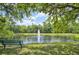 Scenic pond view with a fountain, lush greenery, and a park bench under the shade of mature trees at 12210 Goldenrod Ave, Bradenton, FL 34212