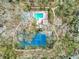 A bird's-eye view of a lush property featuring a pool, hot tub, and tennis court surrounded by mature trees at 1490 Mahogany Ln # 706, Palm Harbor, FL 34683