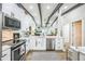 Well-lit kitchen with white cabinets, stainless steel appliances, and dark wood ceiling beams at 1490 Mahogany Ln # 706, Palm Harbor, FL 34683