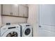 Modern laundry room featuring a new Whirlpool washer and dryer with cabinets above at 17917 Tavernside Trl, Lakewood Ranch, FL 34211