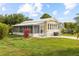 Charming yellow home with a screen porch, green lawn and colorful foliage in a sunny setting at 182 Crown Point Dr, Nokomis, FL 34275