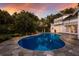 Backyard swimming pool amidst lush landscaping and flagstone deck under a colorful sky at 1829 Bougainvillea St, Sarasota, FL 34239