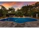 Backyard oasis with pool, pergola covered lounge, and tropical landscaping under a sunset sky at 1829 Bougainvillea St, Sarasota, FL 34239