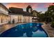 Backyard swimming pool with stone coping and elegant lighting under a colorful sky at 1829 Bougainvillea St, Sarasota, FL 34239
