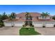 An inviting condo building with a brick driveway, multiple garage doors, and lush, tropical landscaping at 197 Tropicana Dr # 1511, Punta Gorda, FL 33950