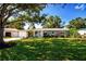 Beautiful one-story home with a lush green lawn, mature tree, and colorful landscaping at 2238 Rose St, Sarasota, FL 34239