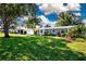 Landscaped front yard showcasing a charming home with mature trees, green lawn, and colorful plants at 2238 Rose St, Sarasota, FL 34239