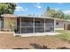 Backyard screened porch with sliding door, patio, mature landscaping, and neutral exterior paint at 2922 Williamsburg St, Sarasota, FL 34231