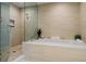 Luxurious bathroom features a soaking tub, stylish fixtures, and travertine-inspired walls at 301 Quay Commons # 1610, Sarasota, FL 34236