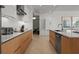 Modern kitchen featuring sleek wood cabinetry, white countertops, and stainless steel appliances with a view of the living area at 301 Quay Commons # 1610, Sarasota, FL 34236