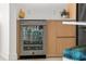 Close-up of a modern beverage center integrated into wood cabinetry with light countertops at 301 Quay Commons # 1610, Sarasota, FL 34236
