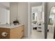 Modern bathroom with wood vanity, adjacent bedroom view, and oval mirror at 301 Quay Commons # 507, Sarasota, FL 34236