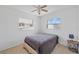 Simple bedroom with a bed, side table, ceiling fan, and windows allowing natural light to fill the space at 309 Glen Oak Rd, Venice, FL 34293