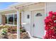 Close-up of the front door with a small window, surrounded by beautiful, colorful flowers at 309 Glen Oak Rd, Venice, FL 34293
