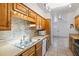 Functional kitchen with wooden cabinets, stainless steel sink, and included dishwasher at 309 Glen Oak Rd, Venice, FL 34293