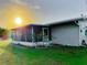 Exterior view of the home, including a screened-in porch and landscaping with a small tree at 389 Millport Nw St, Port Charlotte, FL 33948