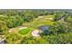Scenic aerial view of a golf course with mature trees, sand traps, and a tranquil pond surrounded by lush greenery at 4487 Glebe Farm Rd, Sarasota, FL 34235