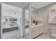 Bright bathroom featuring a large mirror, a white vanity, and patterned wallpaper leading to a bedroom with outdoor views at 4487 Glebe Farm Rd, Sarasota, FL 34235