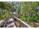 Meandering wooden path winding through lush greenery and trees, offering a serene escape at 4489 Longmeadow # 74, Sarasota, FL 34235