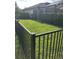 Grassy backyard enclosed with a black metal fence and tall, trimmed hedges for privacy at 4622 Grand Lakeside Dr, Palm Harbor, FL 34684