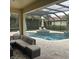 Inviting screened-in pool area with a spa, patio furniture, and lush landscaping at 4622 Grand Lakeside Dr, Palm Harbor, FL 34684
