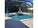 A screened-in pool with hot tub, in-pool lounge chairs, and an umbrella at 4622 Grand Lakeside Dr, Palm Harbor, FL 34684