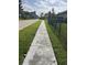 Street view of a long concrete sidewalk along a well maintained lawn and fencing at 4622 Grand Lakeside Dr, Palm Harbor, FL 34684