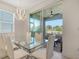 Bright dining area features modern chandelier, glass table with seating, and sliding glass doors to lanai at 4725 Antrim Dr, Sarasota, FL 34240