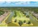 Aerial view of a golf course surrounded by water, lush greenery, and residential buildings on a sunny day at 5320 Hyland Hills Ave # 2214, Sarasota, FL 34241