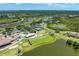 Aerial view of a community with tennis courts, pool, golf course, surrounding lakes, and lush greenery at 5320 Hyland Hills Ave # 2214, Sarasota, FL 34241
