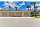 Attached beige garages for a residential building featuring multiple doors and a paved parking area at 5320 Hyland Hills Ave # 2214, Sarasota, FL 34241