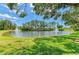 Scenic view of a pond with a welcome sign, surrounded by trees and green grass under a sunny sky at 5320 Hyland Hills Ave # 2214, Sarasota, FL 34241