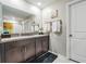 Bright bathroom with dual sinks, granite countertops, dark wood cabinets, and a large mirror at 5426 Rainwood Meadows Dr, Apollo Beach, FL 33572